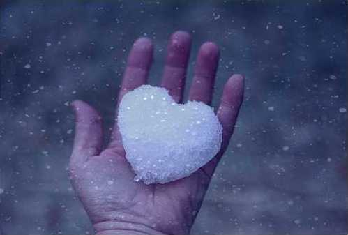 A snow heart held in the palm of a hand.