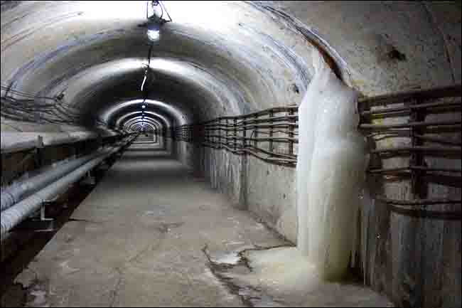 An empty pipe tunnel with a waterfall of ice.